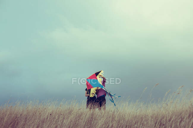 Uomo e donna in piedi in un campo con un aquilone — Foto stock