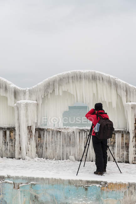Donna che fotografa ghiaccioli su una parete in riva al mare, Bulgaria — Foto stock