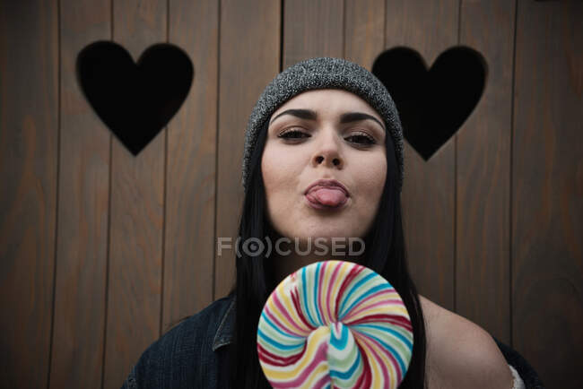 Portrait of a woman with a lollipop sticking out her tongue — Stock Photo