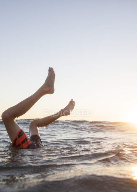 Patas de niño que sobresalen del océano, Condado de Orange, Estados Unidos - foto de stock