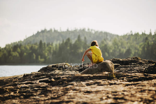 Jovem brincando em rochas perto de um lago — Fotografia de Stock
