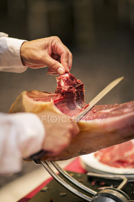 Шеф-повар режет мясо прошутто, обрезанный кадр — стоковое фото