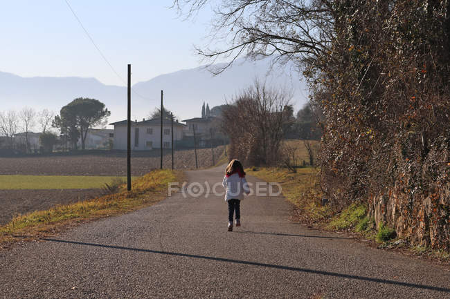 Mädchen läuft eine Landstraße hinunter — Stockfoto