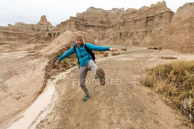 Female hiker showing off muddy boots, Badlands National Park, South Dakota, America, USA — Stock Photo