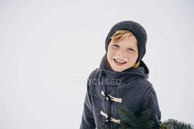 Портрет улыбающегося мальчика, стоящего в снегу — стоковое фото