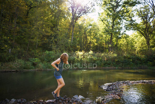 Woman walking along a riverbank — Stock Photo