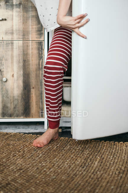 Femme debout près d'un réfrigérateur ouvert dans la cuisine — Photo de stock