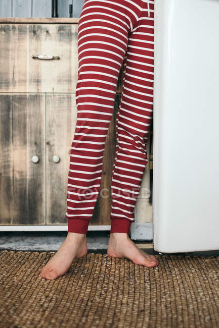 Jambes de femme debout près d'un réfrigérateur dans la cuisine — Photo de stock