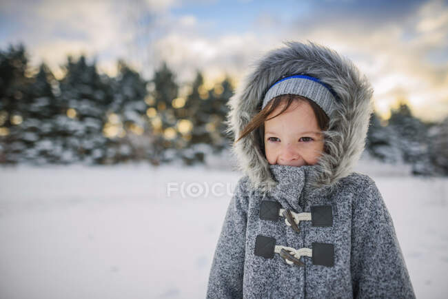 Портрет усміхненої дівчини, що стоїть в снігу в теплому пальто — стокове фото