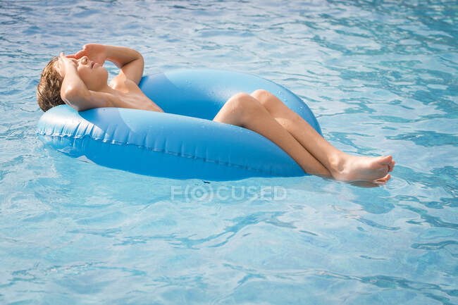 Junge schwimmt in Schwimmbad auf aufblasbarem Gummiring — Stockfoto