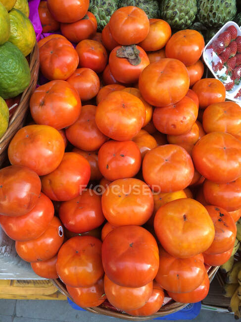 Close-up tiro de pilha de frutos de cáqui que vendem no mercado — Fotografia de Stock