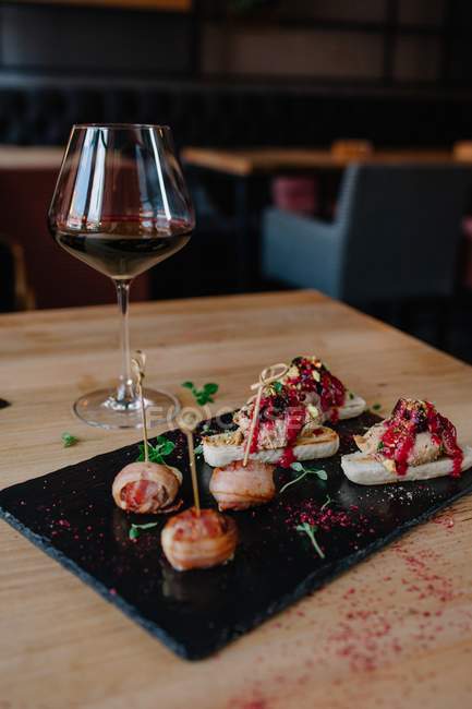 Glass of red wine next to a variety of appetizers — Stock Photo