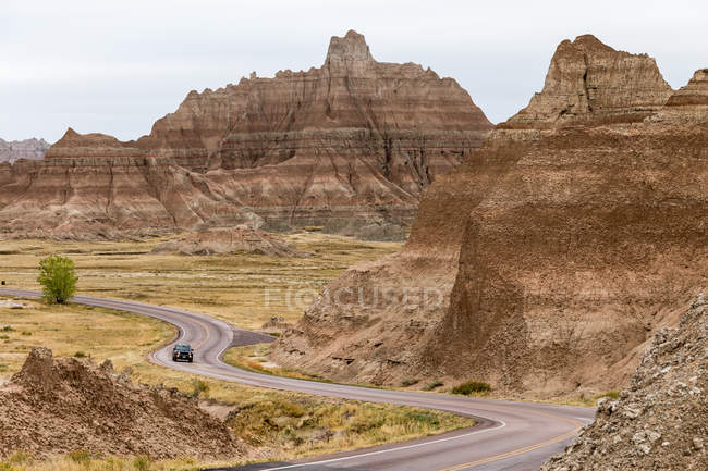 Coche Conducir a lo largo de la carretera sinuosa, Parque Nacional Badlands, Dakota del Sur, América, Estados Unidos - foto de stock