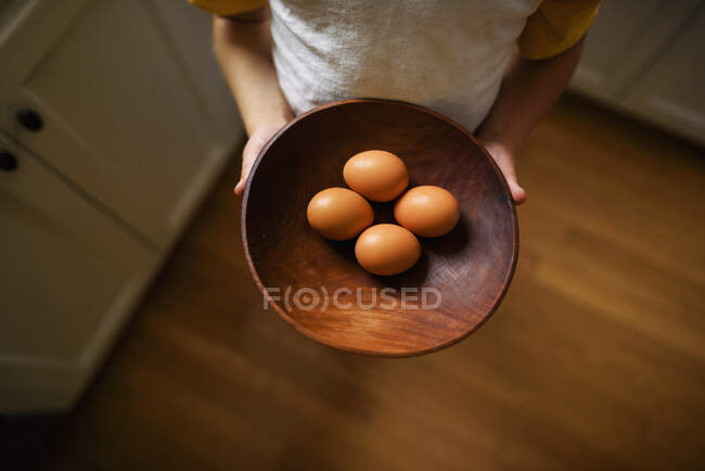 Cropped shot of child holding bowl with eggs — Stock Photo