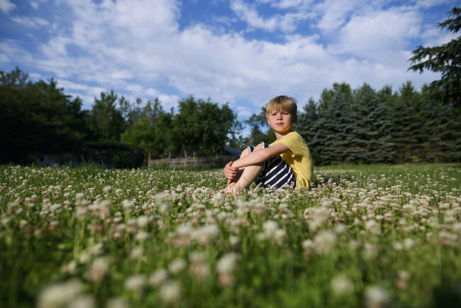 Niño sentado en la hierba en el día soleado - foto de stock