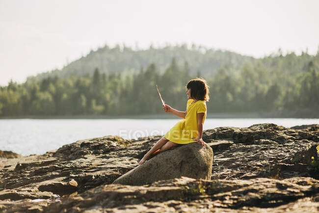 Молодая девушка играет на камнях у озера — стоковое фото