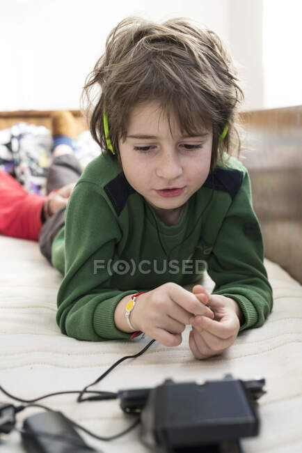Мальчик лежит на кровати и играет в компьютерные игры. — стоковое фото