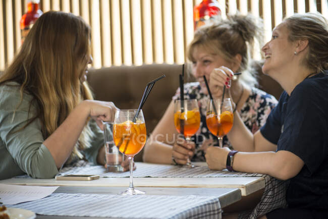 Three women drinking cocktails in a bar — Stock Photo