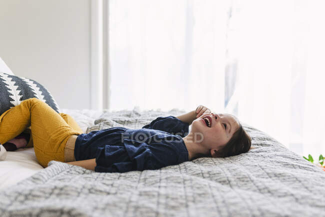 Дівчина лежить на ліжку сміється — стокове фото