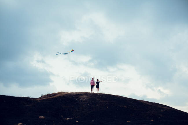 Uomo e donna in piedi in un campo che vola un aquilone — Foto stock