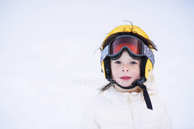 Retrato de una niña sentada en la nieve con un casco de esquí - foto de stock