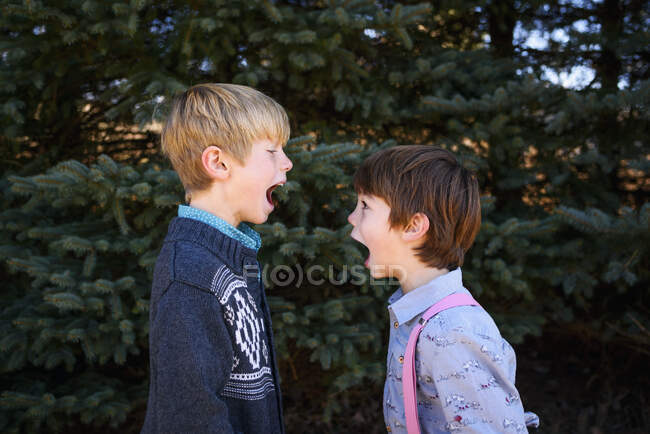 Two boys standing opposite each other with their mouths open — Stock Photo