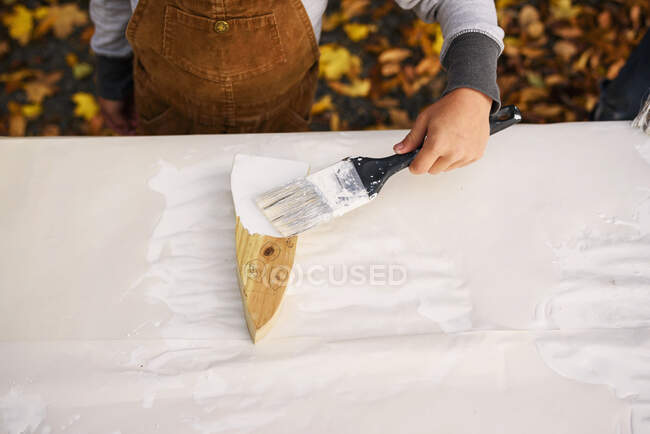 Menino pintando uma decoração fantasma de madeira para o Halloween — Fotografia de Stock