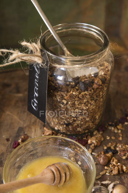 Granola jar with honey over wooden rustic table — Stock Photo