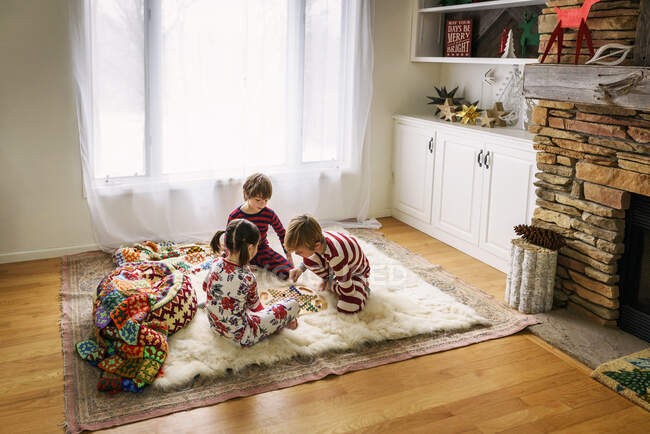 Трое детей сидят на полу и играют в настольную игру. — стоковое фото
