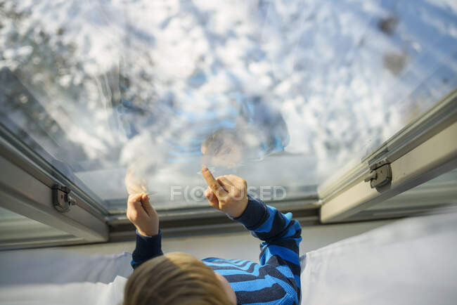 Boy looking out of a window at snow — Stock Photo