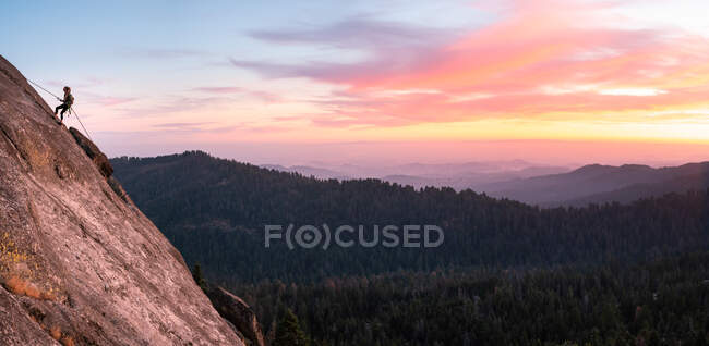 Mujer rapseiling Down a Cliff at Sunset, Sequoia National Park, California, Estados Unidos - foto de stock