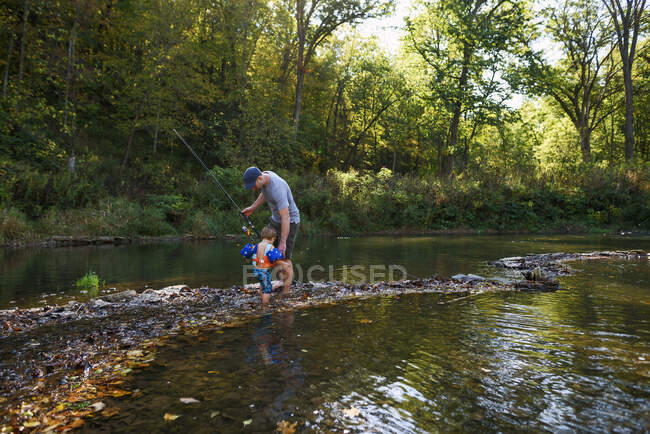 Людина риболовля в річці зі своїм сином — стокове фото