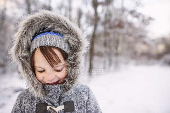 Retrato de una niña sonriente de pie en un paisaje rural de invierno - foto de stock