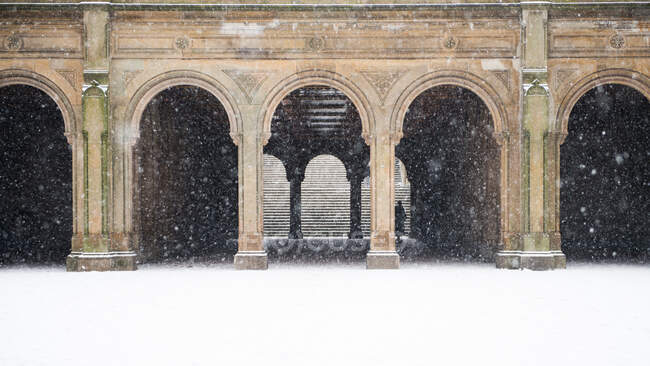 Вважаючи серцем Центрального парку Нью-Йорка, це Бетезда Террас. Жінка йде через арки і виходить зі снігу.. — стокове фото