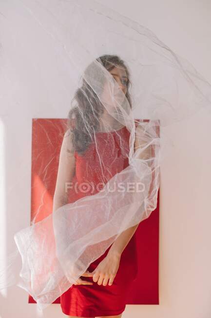 Porträt einer Frau, die an einer roten Wand hinter einem Schleier steht — Stockfoto