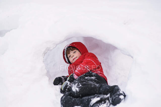 Close-up retrato de menino deitado em um buraco na neve — Fotografia de Stock