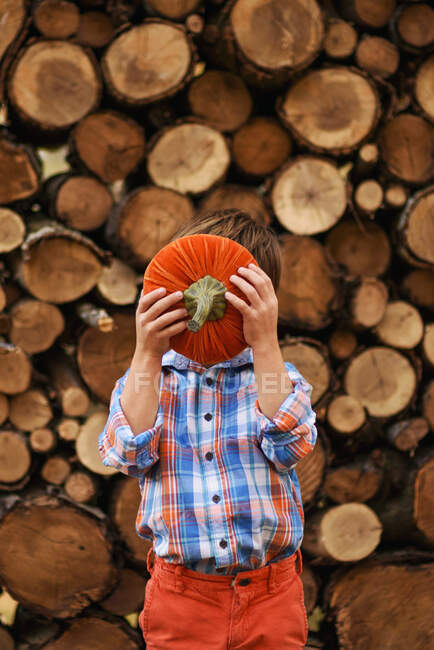 Niño sosteniendo una calabaza en frente de su cara - foto de stock