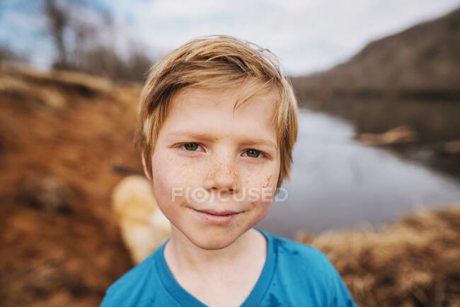 Retrato de um menino sorridente em pé na praia com areia no rosto — Fotografia de Stock