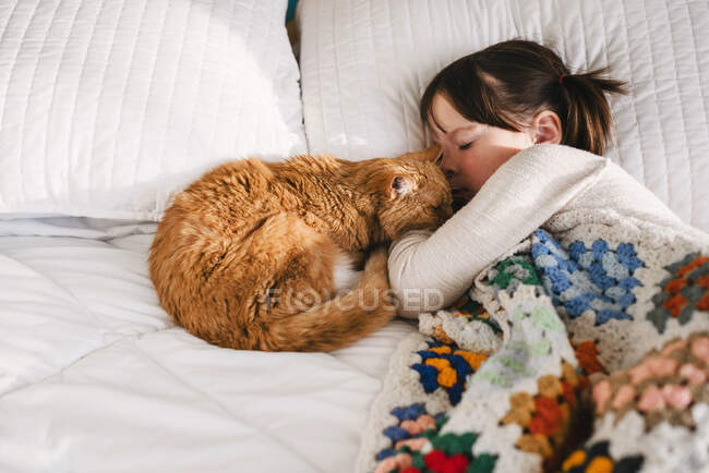 Young girl sleeping on bed with cat — Stock Photo