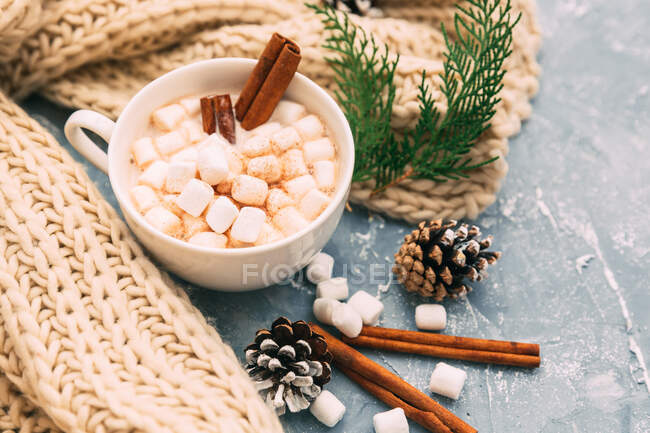Chocolate quente com marshmallows e paus de canela em um fundo de madeira. — Fotografia de Stock