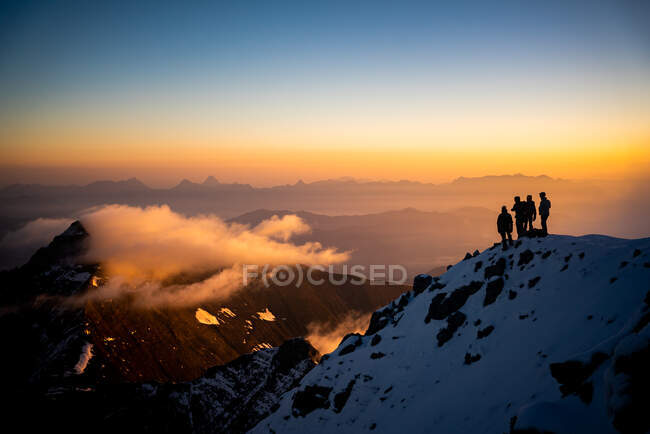 Grupo de personas en las montañas pico con cielo al atardecer - foto de stock