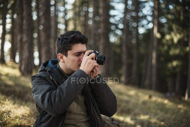 Hombre de pie en el bosque tomando fotos - foto de stock