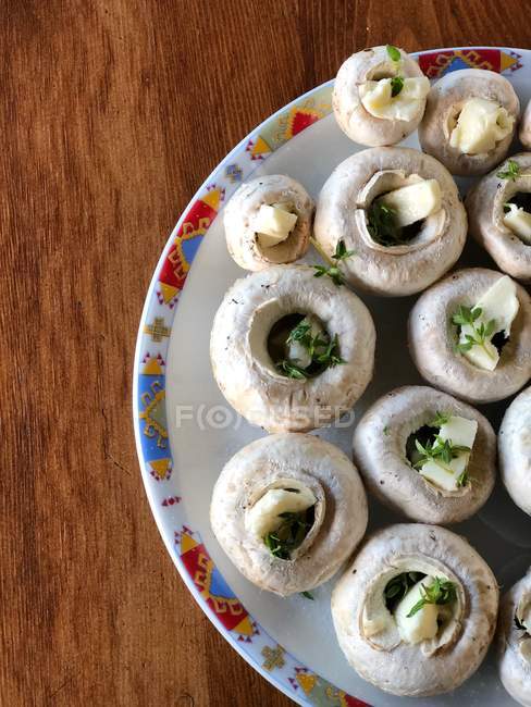 Cogumelos crus recheados com manteiga e tomilho em um prato pronto para cozinhar — Fotografia de Stock