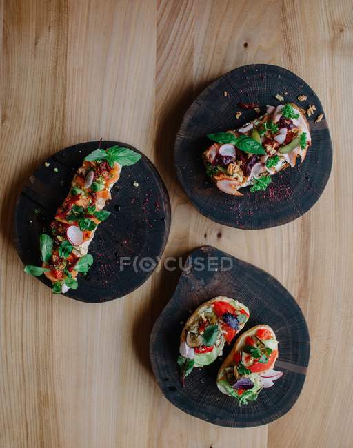Три види відкритих бутербродів на дерев'яному столі — стокове фото