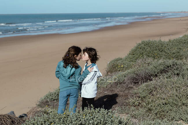 Brother and sister standing on beach kissing, Spain — Stock Photo