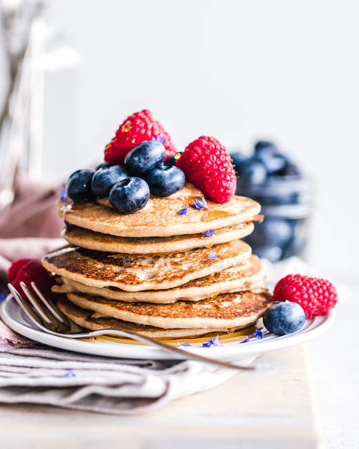 Stapel Pfannkuchen mit Blaubeeren, Himbeeren und Ahornsirup — Stockfoto