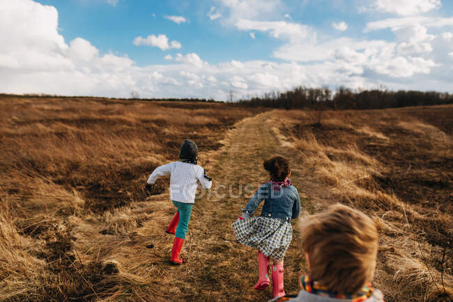 Glückliche Kinder auf dem Herbstfeld unter wolkenverhangenem Himmel — Stockfoto