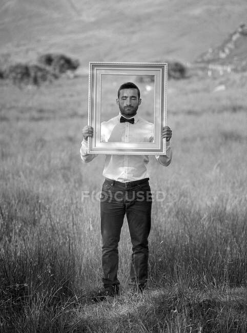 Portrait d'un homme tenant un cadre photo devant son visage, Irlande — Photo de stock