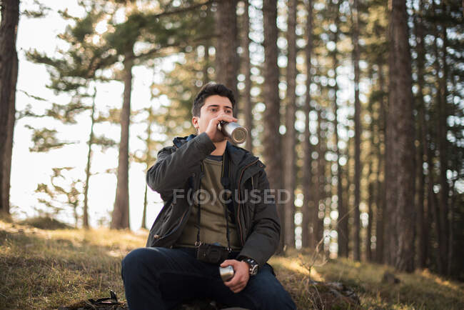 Uomo seduto nella foresta acqua potabile — Foto stock