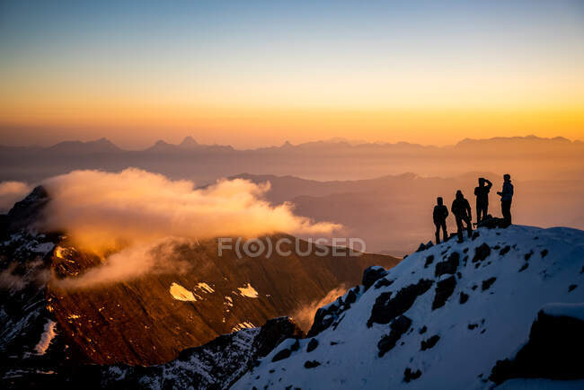 Group of people on mountains peak with sunset sky — Stock Photo